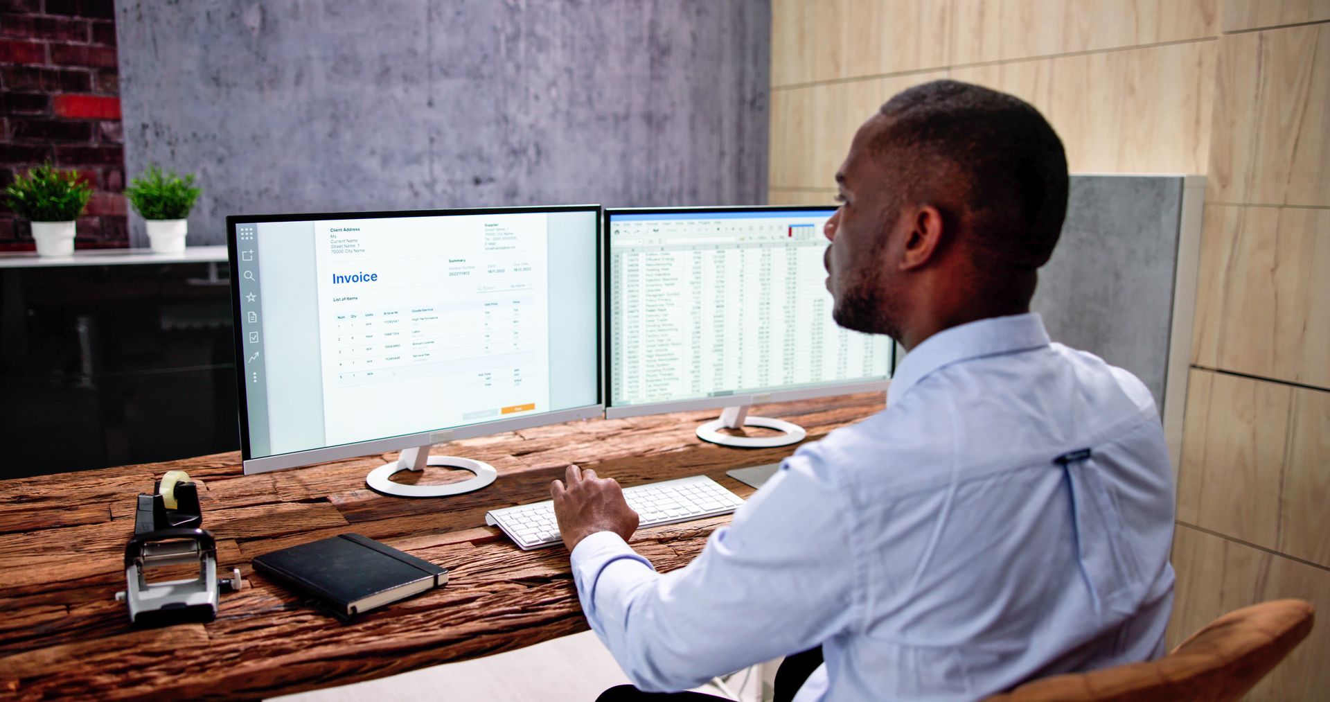Person working at a desk with dual monitors in a wood-paneled office, viewed from behind.